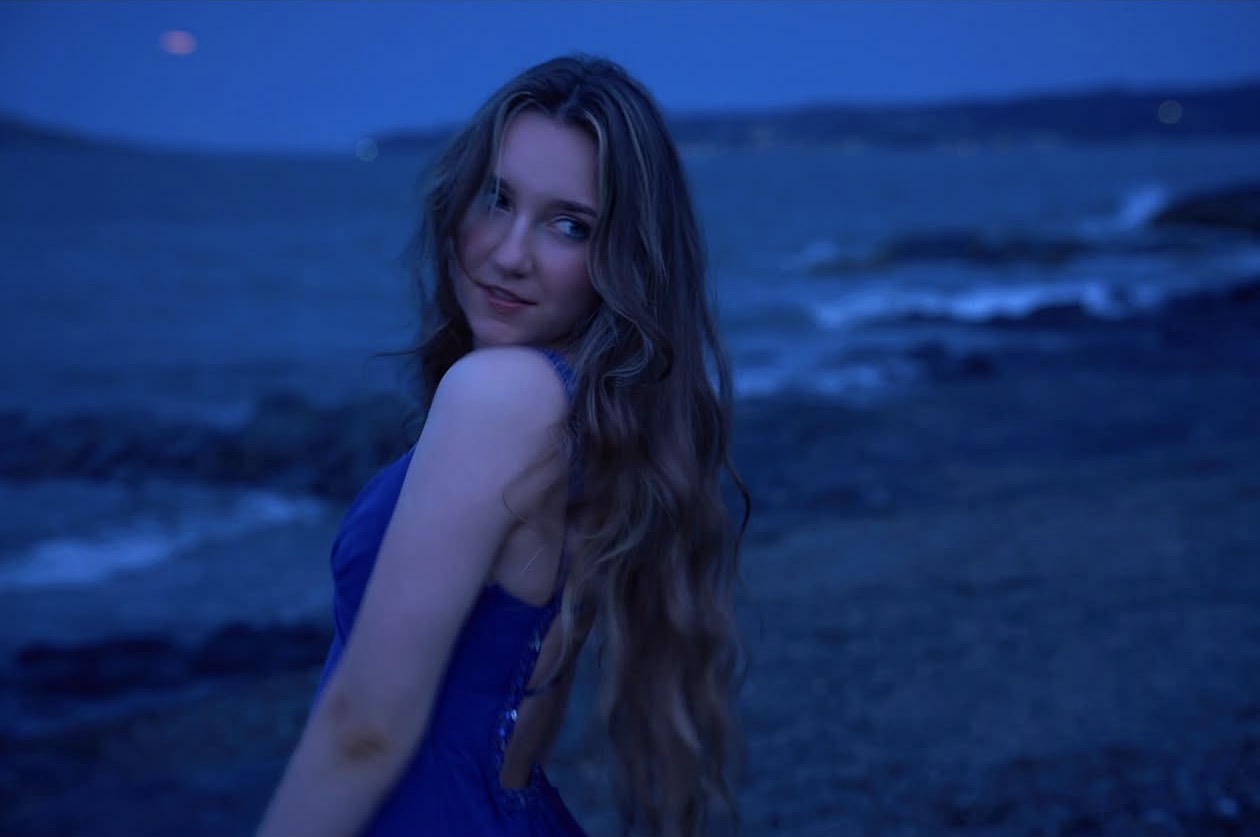 Liza looking over her shoulder by the sea at dusk